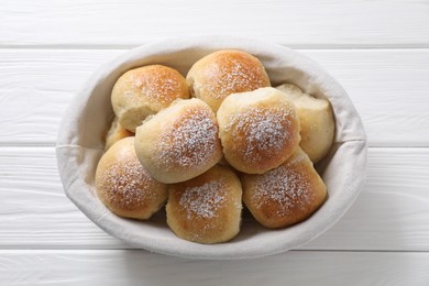 Photo of Delicious dough balls in basket on white wooden table, top view