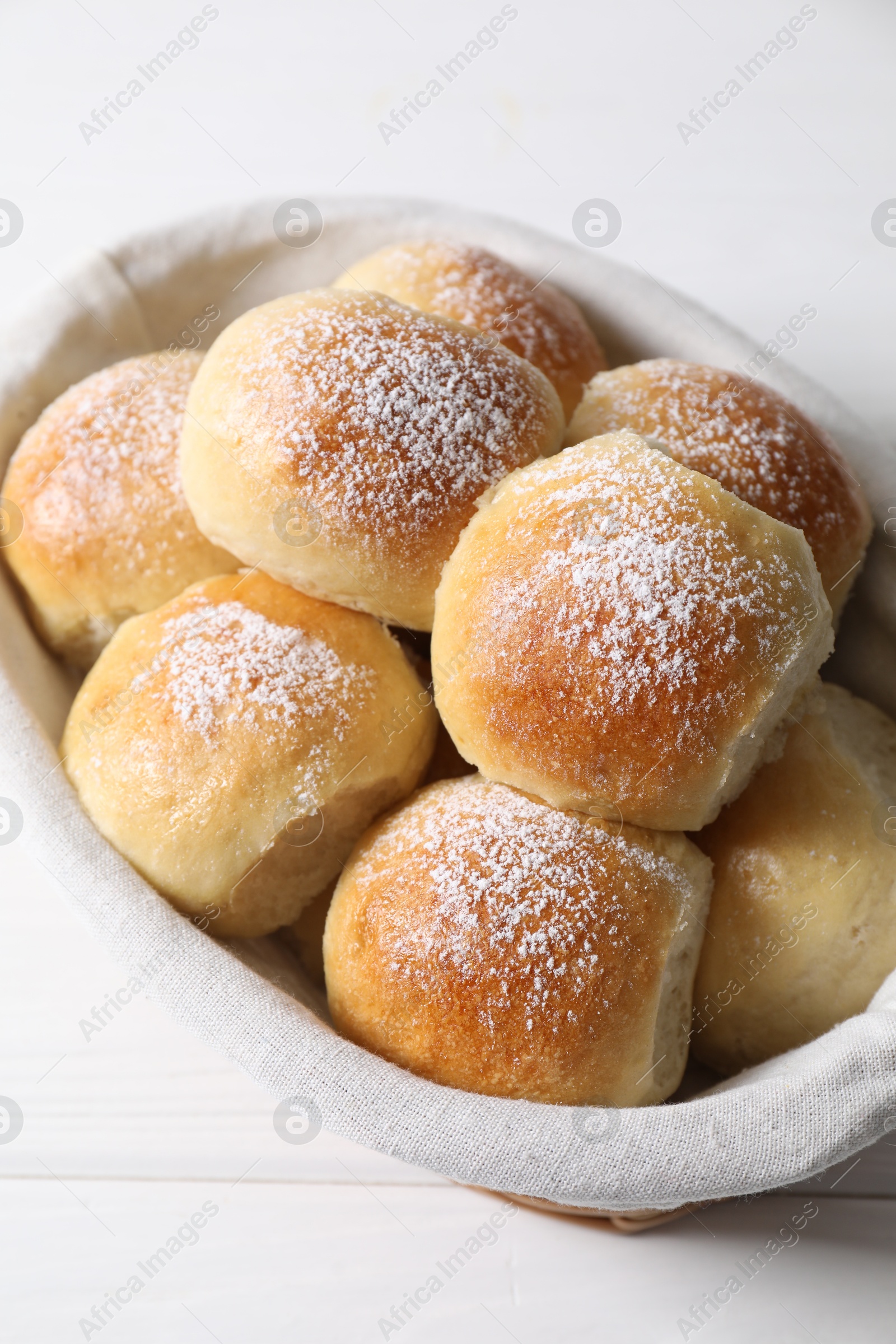 Photo of Delicious dough balls in basket on white wooden table, above view