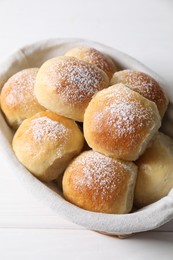 Photo of Delicious dough balls in basket on white wooden table, above view