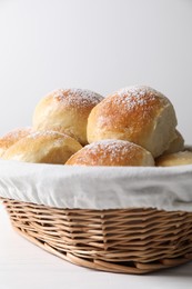 Photo of Delicious dough balls in basket on white wooden table