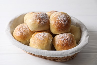 Photo of Delicious dough balls in basket on white wooden table