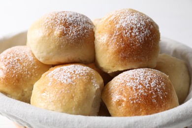 Photo of Delicious dough balls in basket on light background, closeup