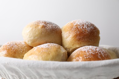 Delicious dough balls in basket on light background