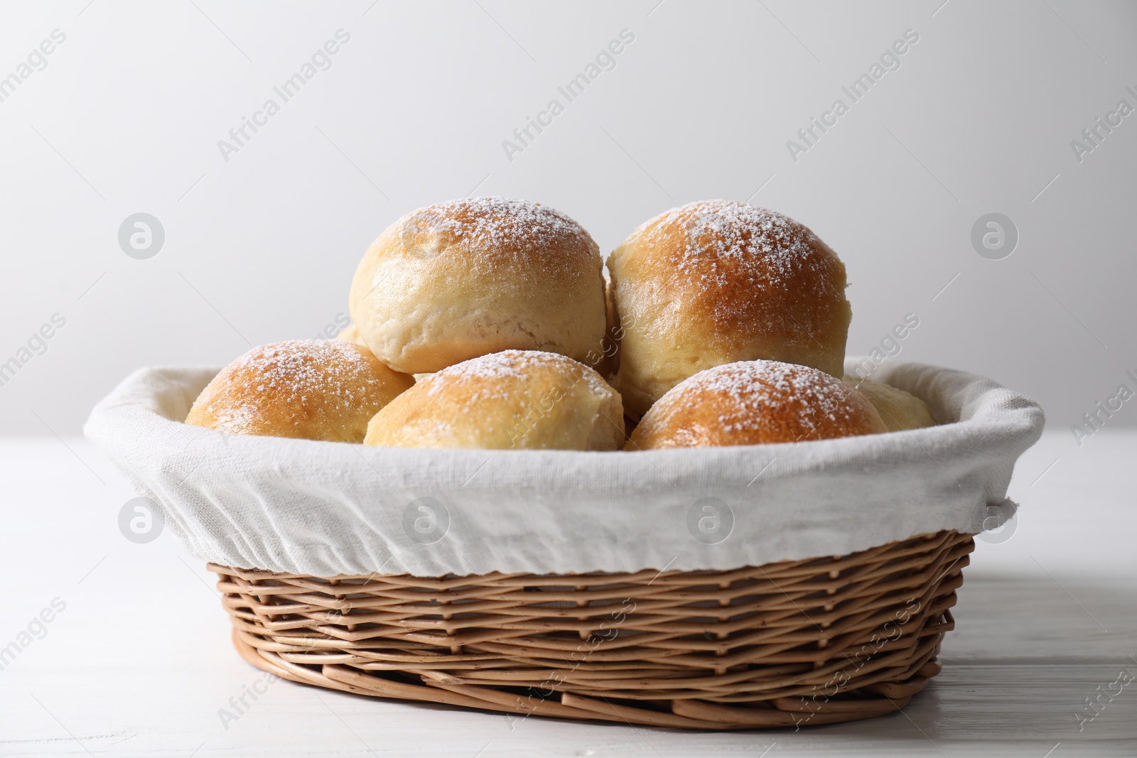 Photo of Delicious dough balls in basket on white wooden table