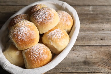 Delicious dough balls in basket on wooden table, space for text