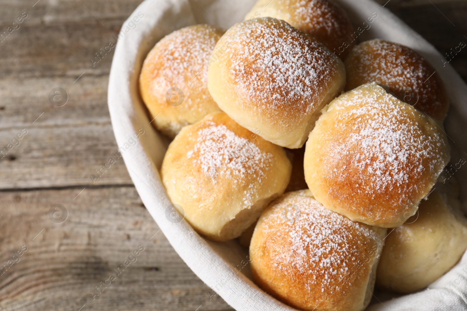 Photo of Delicious dough balls in basket on wooden table, above view. Space for text