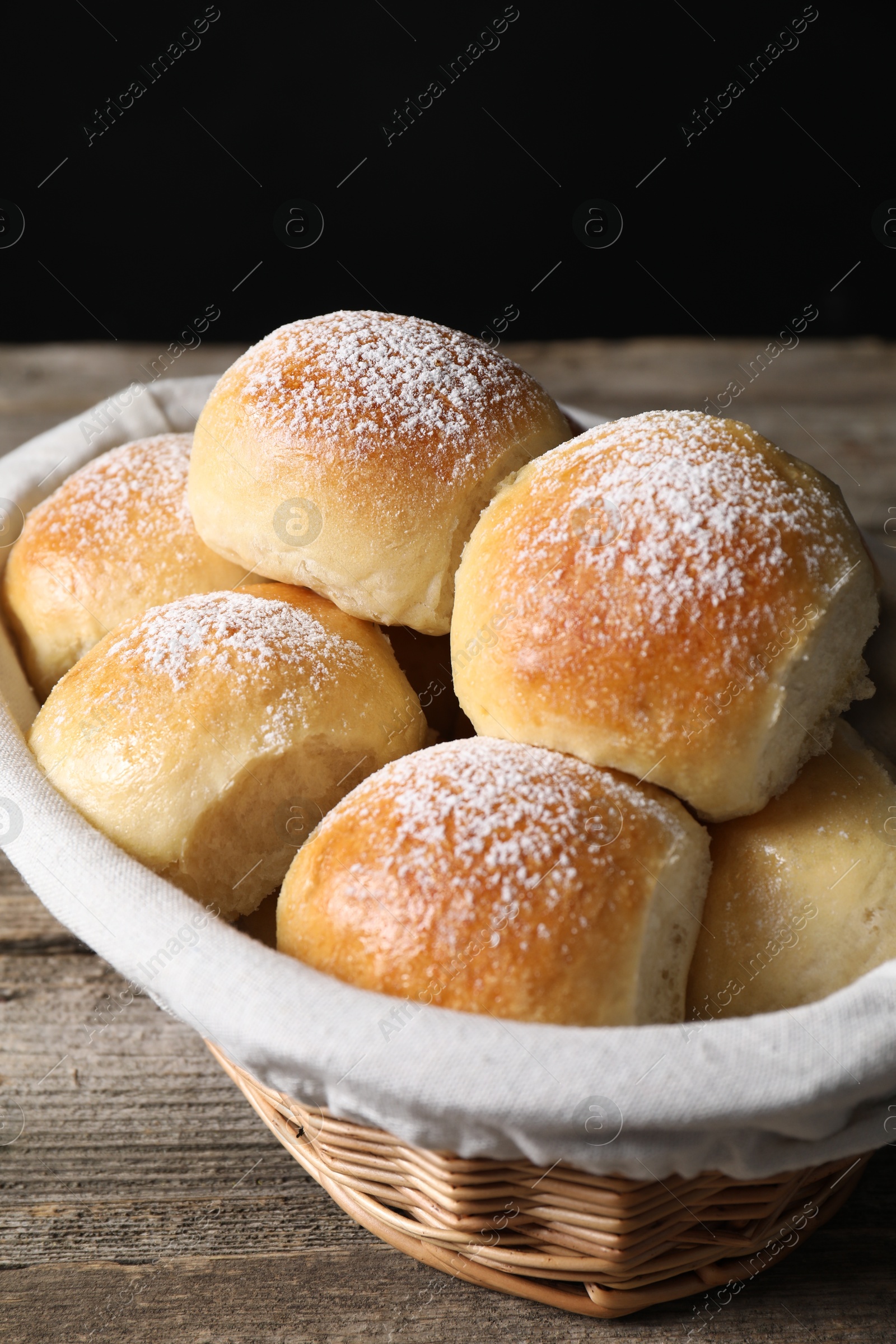 Photo of Delicious dough balls in basket on wooden table, closeup