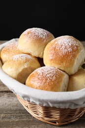 Delicious dough balls in basket on wooden table, closeup