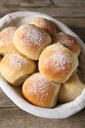 Delicious dough balls in basket on wooden table, top view