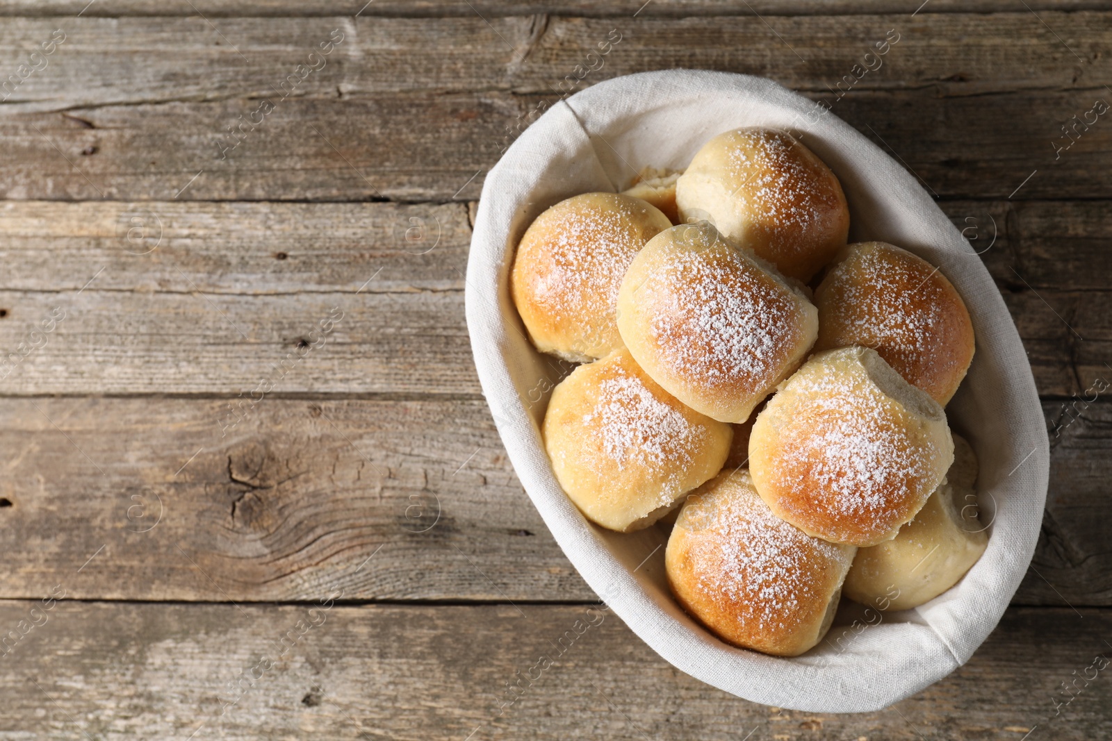 Photo of Delicious dough balls in basket on wooden table, top view. Space for text