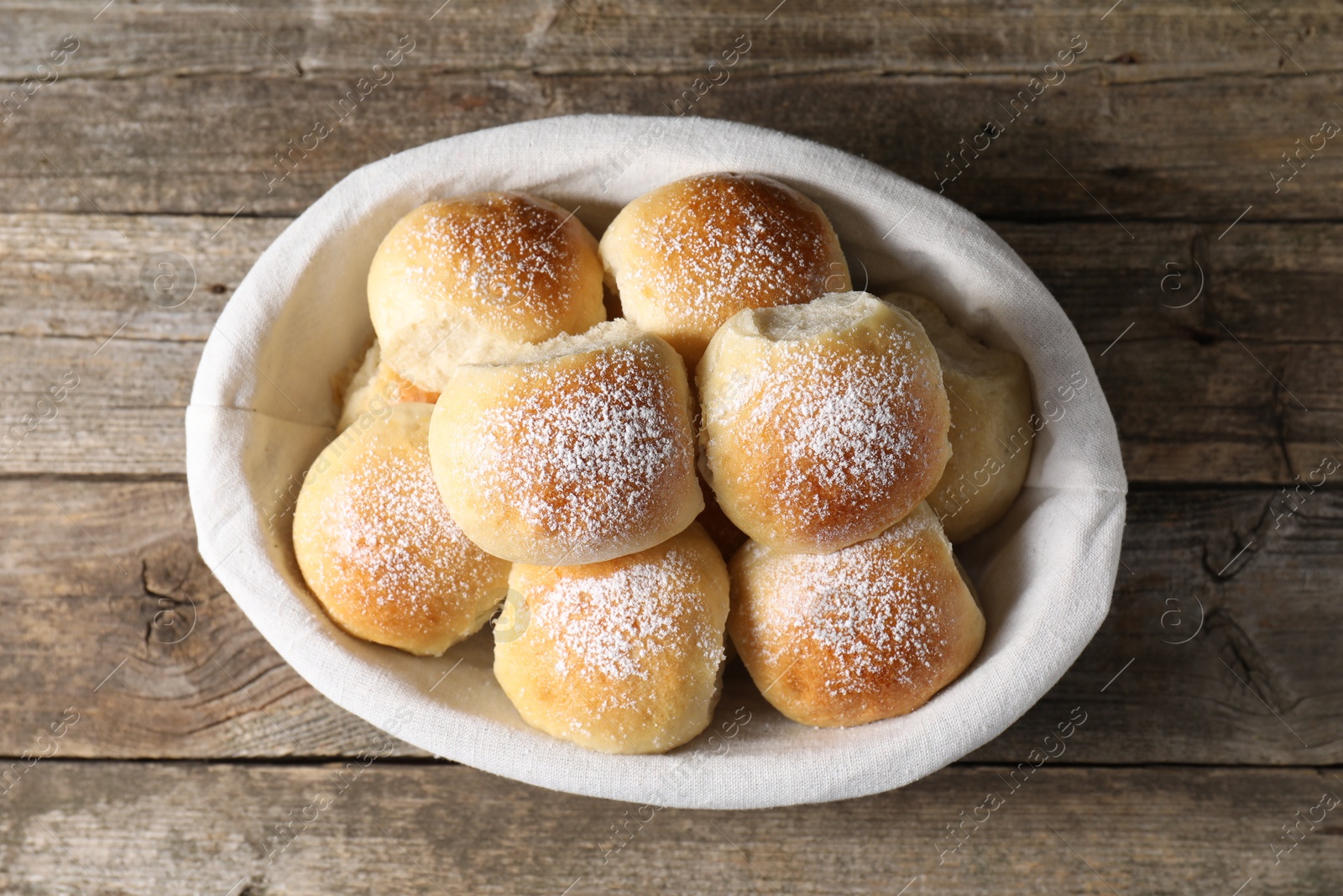 Photo of Delicious dough balls in basket on wooden table, top view