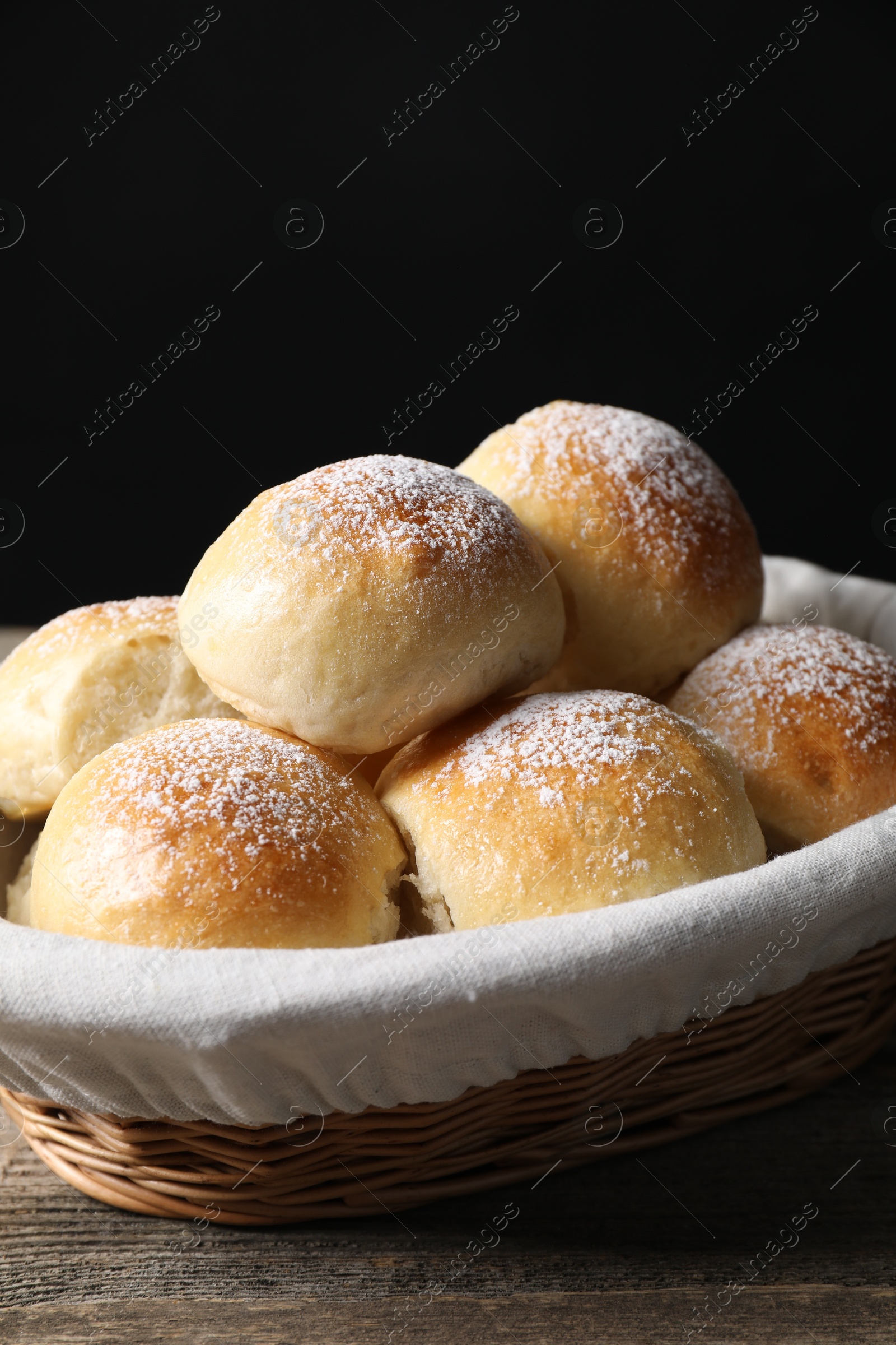 Photo of Delicious dough balls in basket on wooden table, closeup