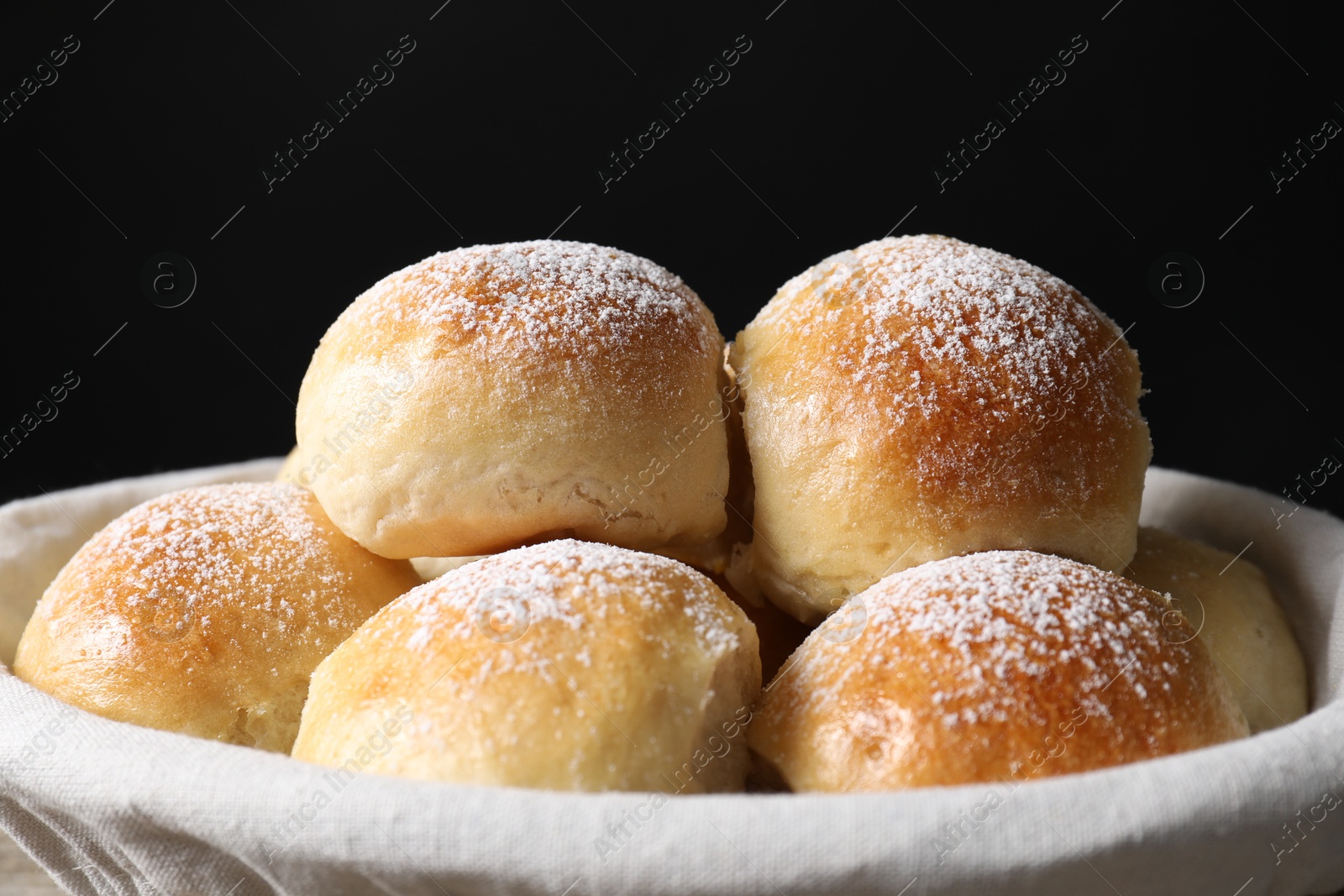 Photo of Delicious dough balls in basket on black background, closeup