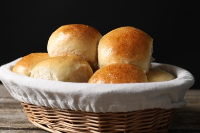 Delicious dough balls in basket on wooden table, closeup