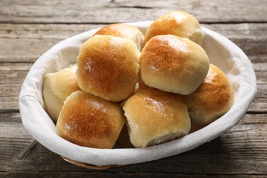 Photo of Delicious dough balls in basket on wooden table, closeup