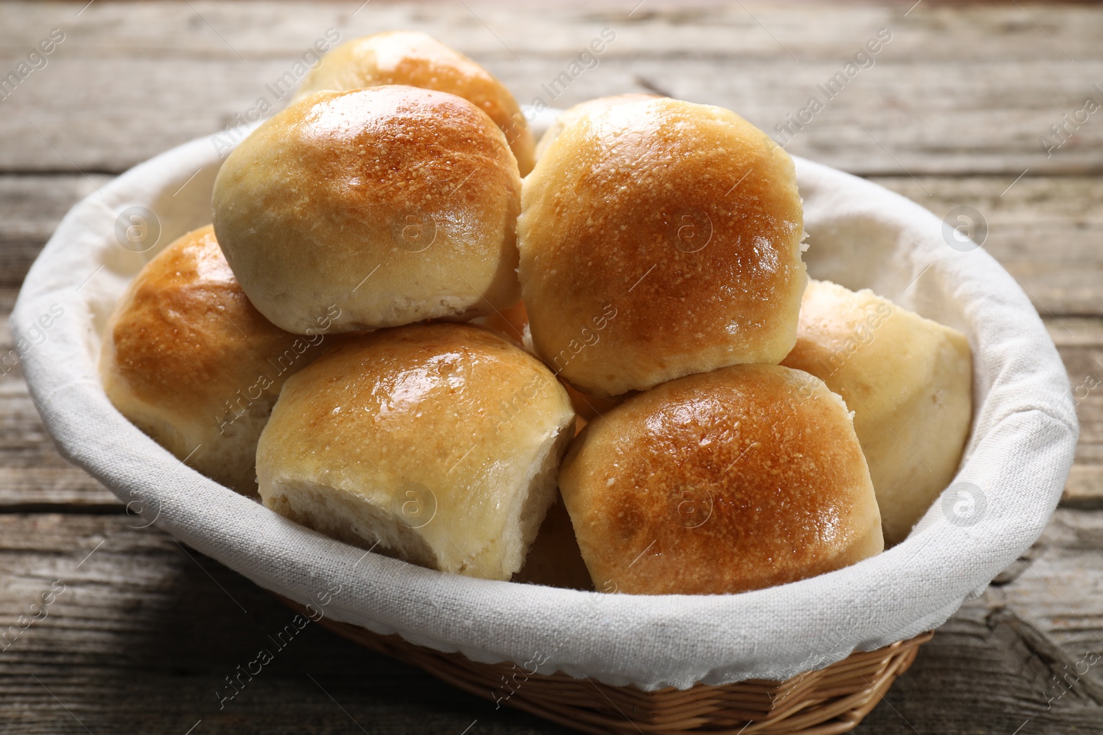 Photo of Delicious dough balls in basket on wooden table, closeup