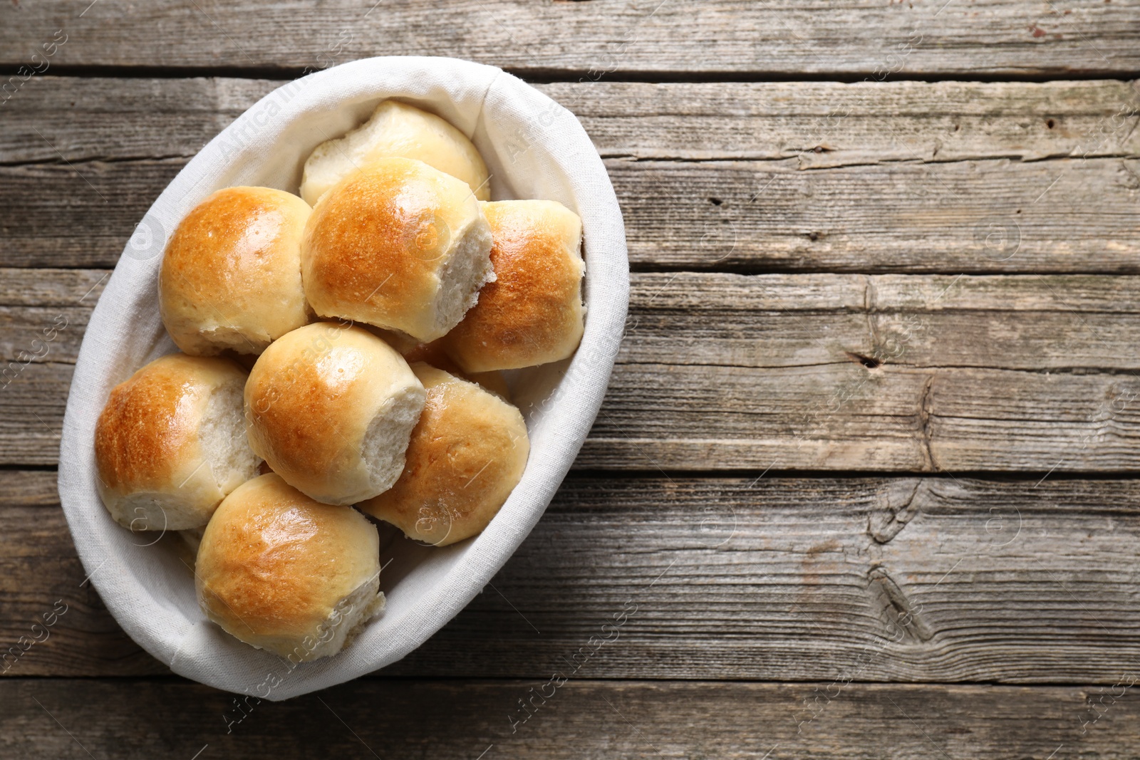 Photo of Delicious dough balls in basket on wooden table, top view. Space for text