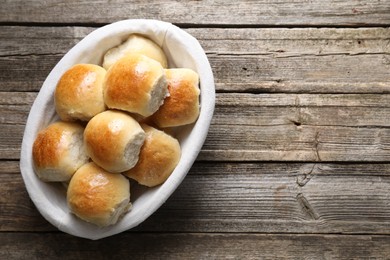 Photo of Delicious dough balls in basket on wooden table, top view. Space for text