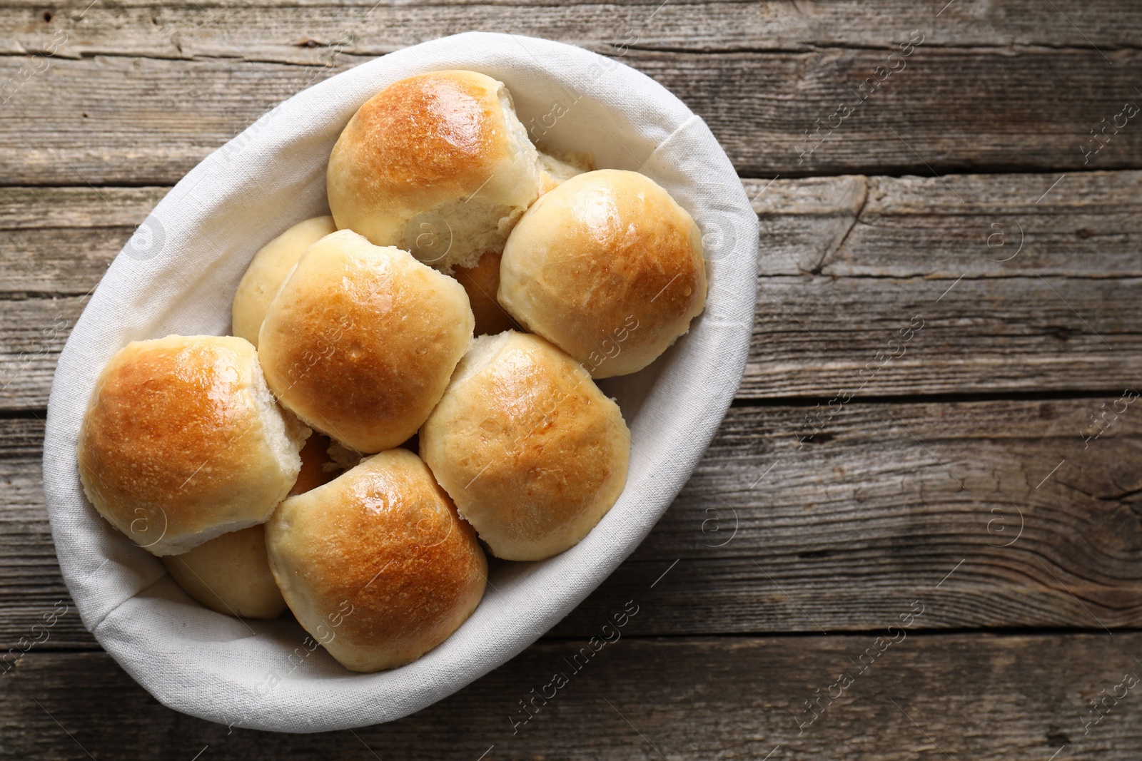 Photo of Delicious dough balls in basket on wooden table, top view. Space for text