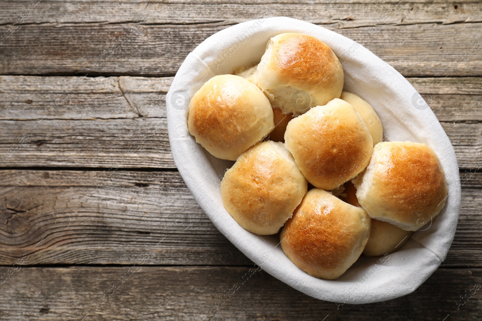 Photo of Delicious dough balls in basket on wooden table, top view. Space for text