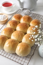 Photo of Delicious dough balls, powdered sugar, tea, teapot and gypsophila flowers on white wooden table