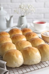 Photo of Delicious dough balls, powdered sugar, tea, teapot and gypsophila flowers on white table