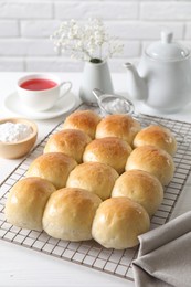 Delicious dough balls, powdered sugar, tea, teapot and gypsophila flowers on white wooden table