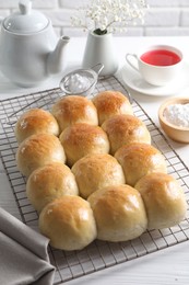 Delicious dough balls, powdered sugar, tea, teapot and gypsophila flowers on white wooden table