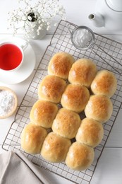 Photo of Delicious dough balls, powdered sugar, tea and gypsophila flowers on white wooden table, top view