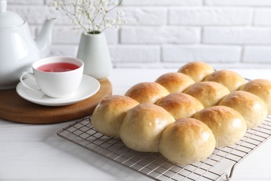 Photo of Delicious dough balls, tea, teapot and gypsophila flowers on white wooden table