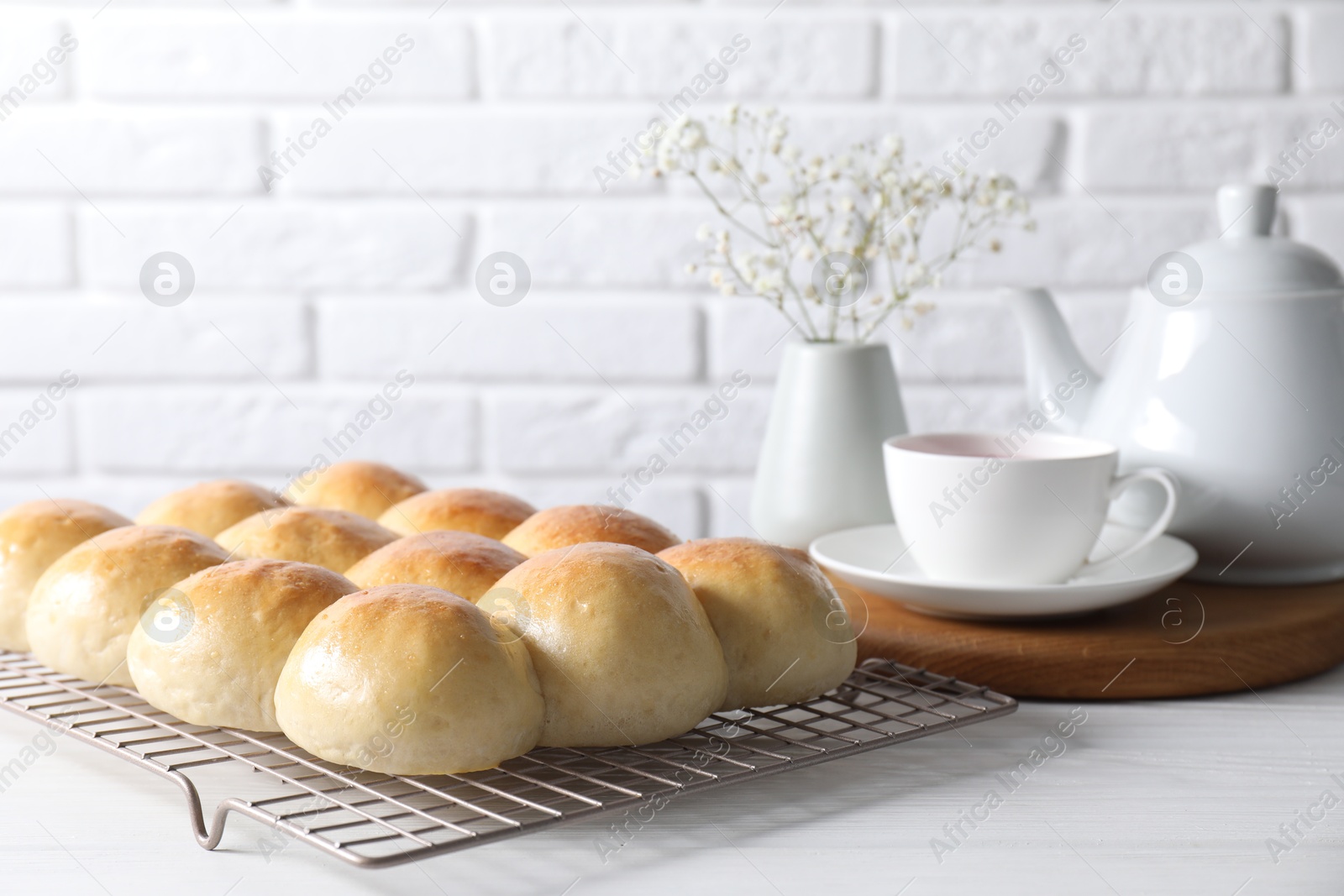 Photo of Delicious dough balls, tea, teapot and gypsophila flowers on white wooden table