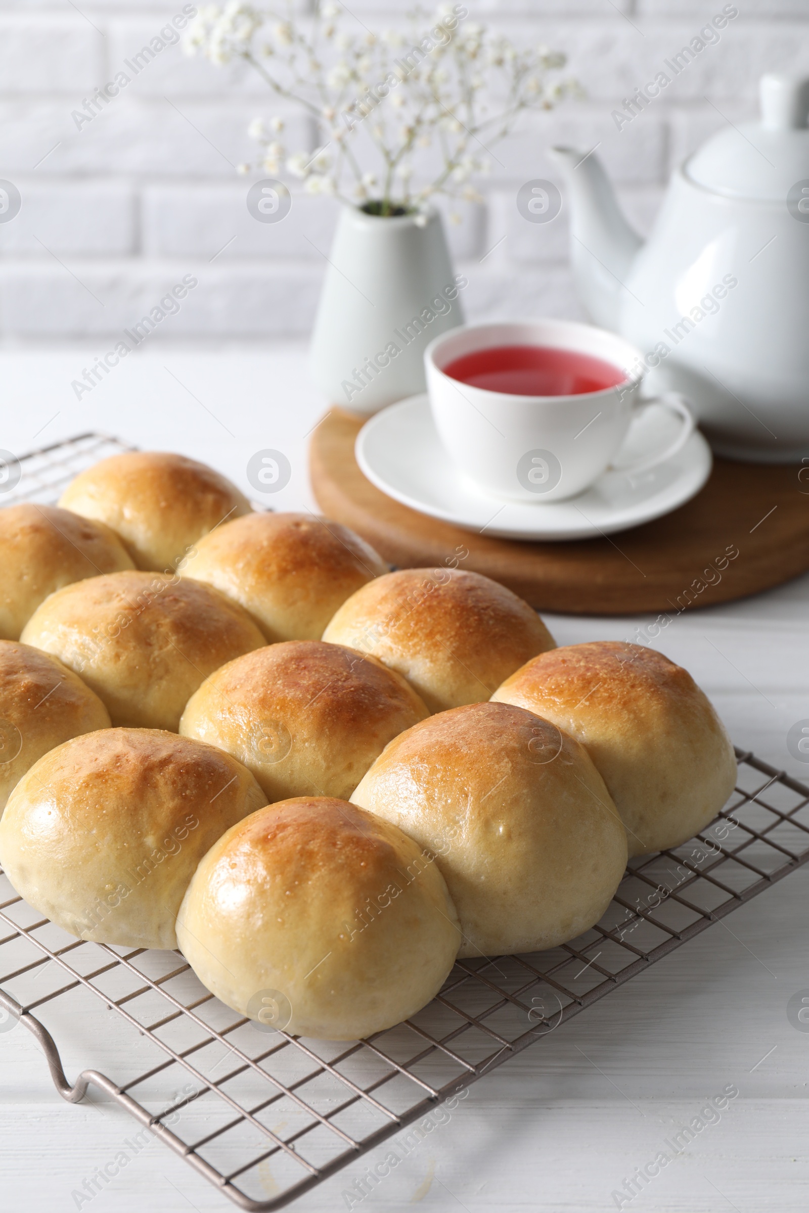 Photo of Delicious dough balls, tea, teapot and gypsophila flowers on white wooden table