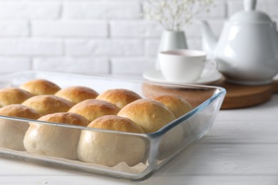 Delicious dough balls in baking dish on white wooden table