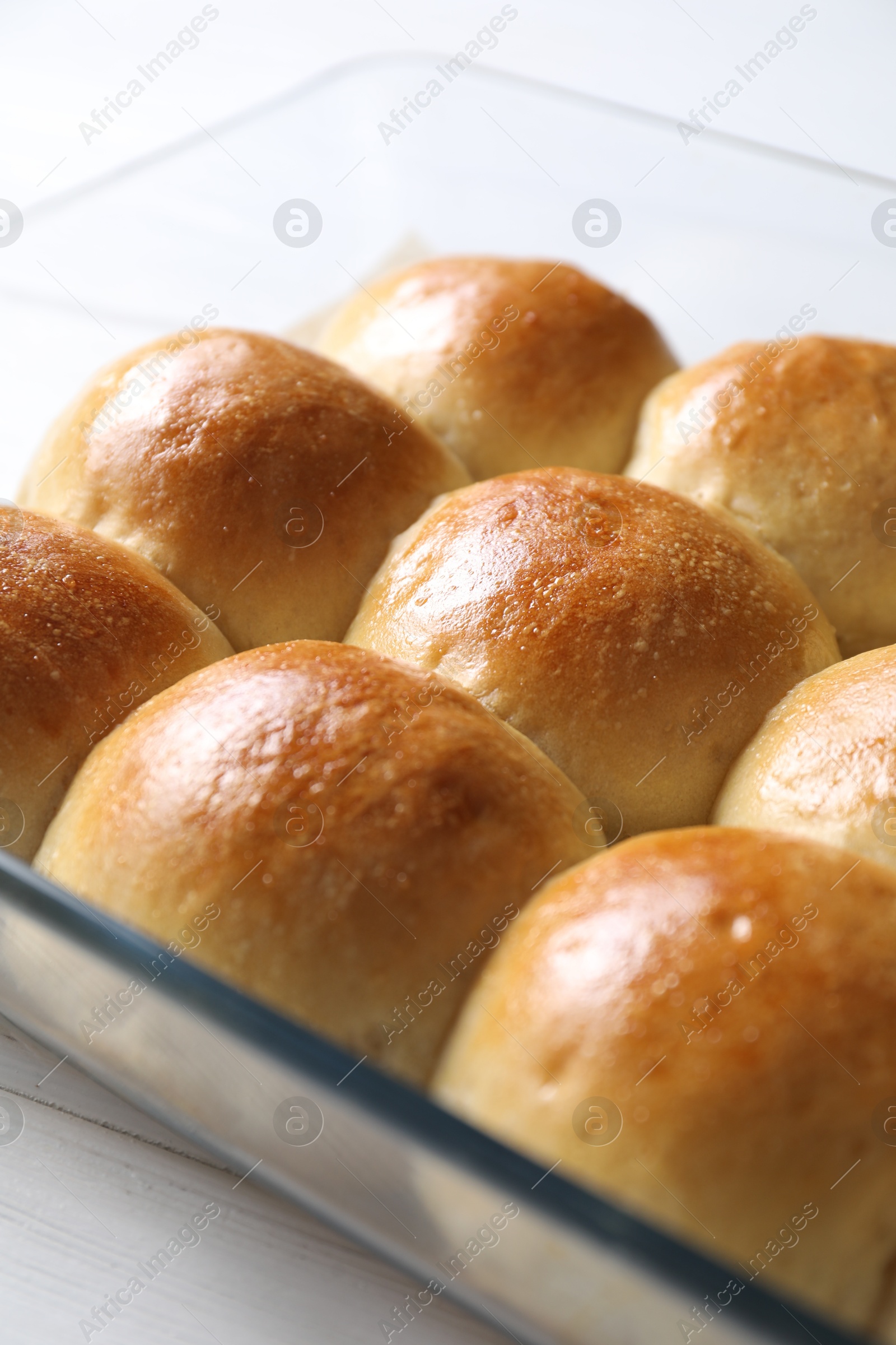 Photo of Delicious dough balls in baking dish on white wooden table, closeup