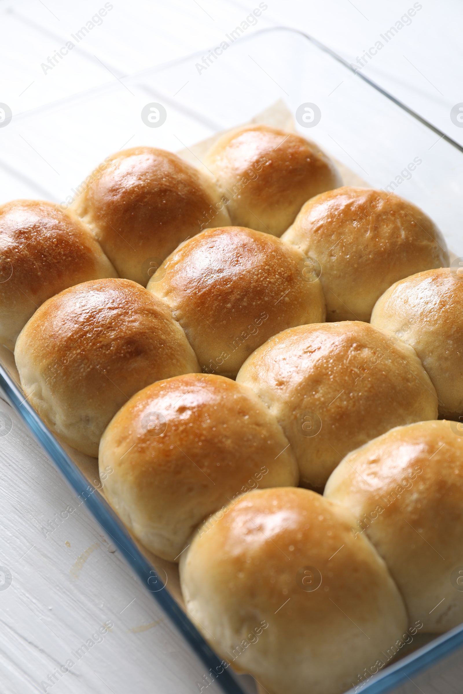 Photo of Delicious dough balls in baking dish on white wooden table, closeup