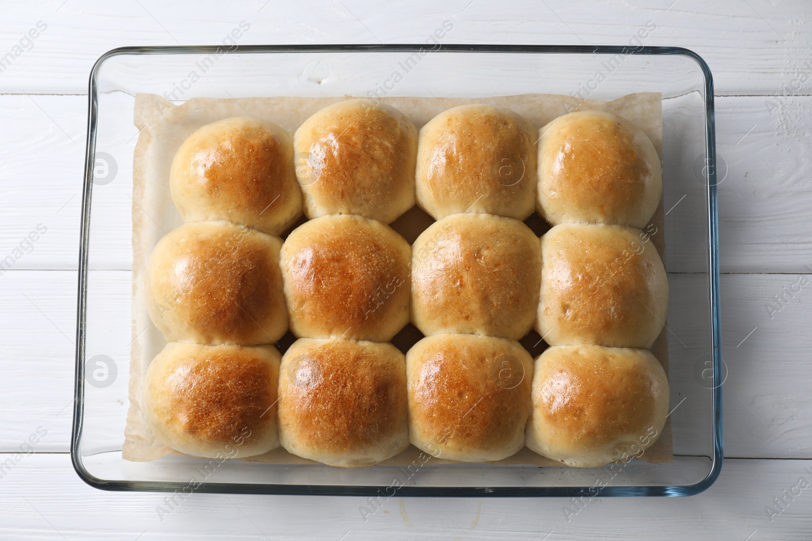 Photo of Delicious dough balls in baking dish on white wooden table, top view