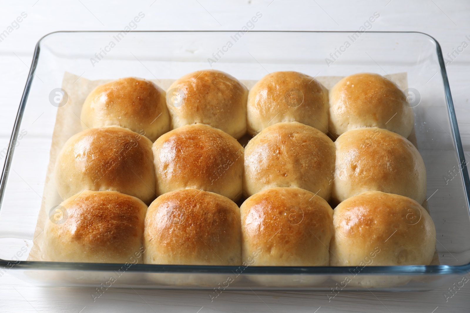 Photo of Delicious dough balls in baking dish on white wooden table