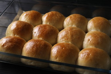 Photo of Delicious dough balls in baking dish on black wooden table, closeup