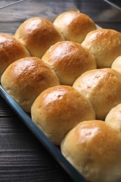 Photo of Delicious dough balls in baking dish on black wooden table