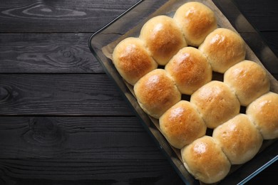 Delicious dough balls in baking dish on black wooden table, top view. Space for text