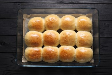 Delicious dough balls in baking dish on black wooden table, top view