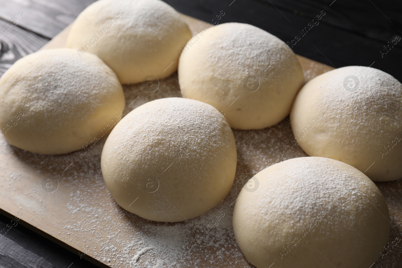 Photo of Raw dough balls on black wooden table, closeup