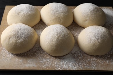 Photo of Raw dough balls with flour on table