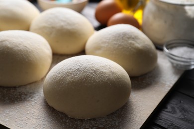 Photo of Raw dough balls on black wooden table, closeup