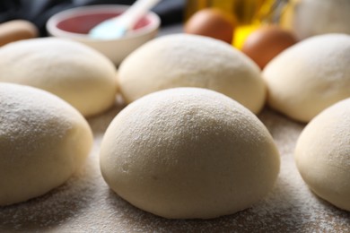 Photo of Raw dough balls with flour on table, closeup