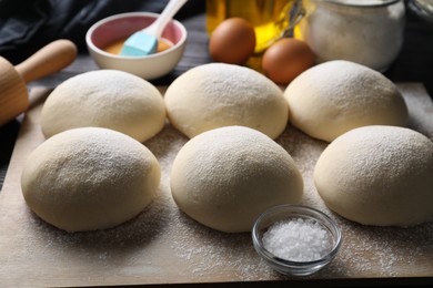 Photo of Raw dough balls, yolk, salt, flour, eggs and rolling pin on table