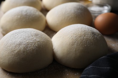 Raw dough balls with flour on table, closeup