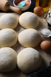 Raw dough balls, yolk, salt, flour, eggs and rolling pin on table