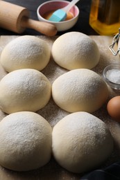 Raw dough balls, yolk, salt, flour, eggs and rolling pin on table