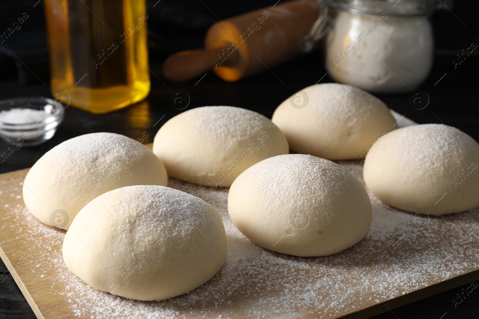 Photo of Raw dough balls with flour on table